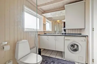 a bathroom with a toilet and a washing machine at LK539-Lokken-Sylviavej-27 in Løkken