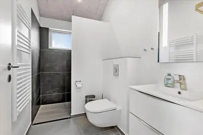 a white bathroom with a toilet and a sink at LK1824-Lokken-Marthasvej-16 in Løkken