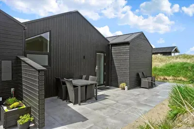 a black house with a patio with a table and chairs at LK1824-Lokken-Marthasvej-16 in Løkken