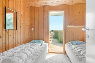 a room with two beds and a door with a porch at LK1054-Lokken-Lottesvej-22 in Løkken