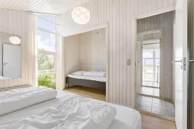 a white bedroom with a bed and a mirror at LK552-Lokken-Ornegaardsvej-14 in Løkken