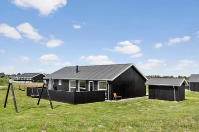 a black house in a field with signs in the grass at LK1979-Lokken-Kringelbaekvej-42 in Løkken