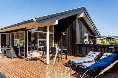 a house with a wooden deck with blue couches at LK2095-Lokken-Mievej-28 in Løkken