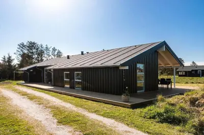 a black house with a porch on a dirt road at LK2095-Lokken-Mievej-28 in Løkken