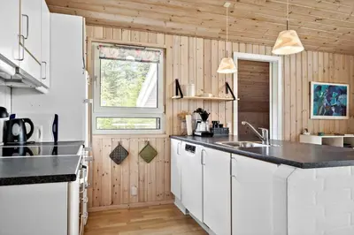 a kitchen with white cabinets and a black counter top at LK350-Lokken-Piasvej-11 in Løkken
