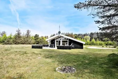 a small black building in a field with a grass yard at LK350-Lokken-Piasvej-11 in Løkken