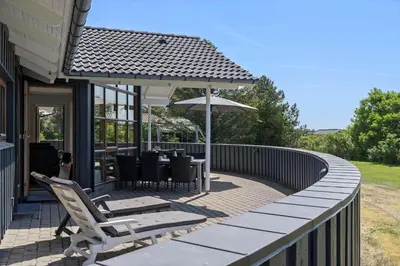 a patio with a table and chairs and an umbrella at LK1948-Lokken-Karinavej-48 in Løkken