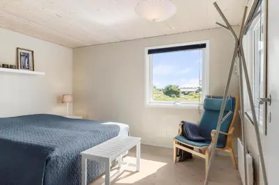 a bedroom with a bed and a chair and a window at LK1394-Lokken-Lisevej-5 in Løkken