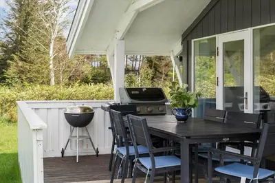 a porch with a table and chairs and a grill at LK2046-Lokken-Kristavej-25 in Løkken