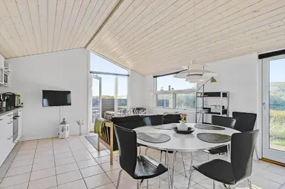 a dining room and living room with a table and chairs at LK281-Lokken-Lonesvej-5 in Løkken