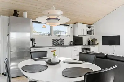 a kitchen with a table with chairs and a refrigerator at LK281-Lokken-Lonesvej-5 in Løkken
