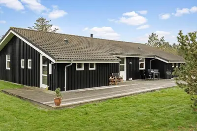 a black house with a deck in front of it at LK1325-Lokken-Karinavej-59 in Løkken