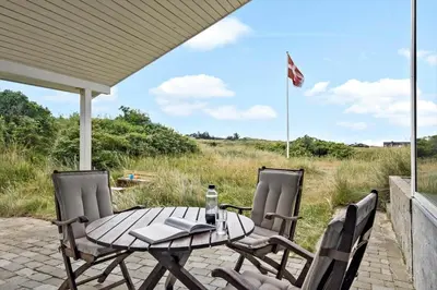 a table and chairs on a patio with a flag at LK1786-Lokken-Nannasvej-18 in Løkken