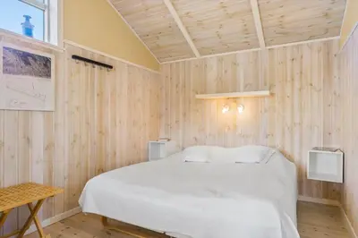 a bedroom with a white bed and wooden walls at LK322-Lokken-Ornegaardsvej-27 in Løkken