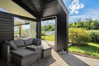 a screened in porch with a couch on a deck at LK1946-Lokken-Kringelbaekvej-5 in Løkken