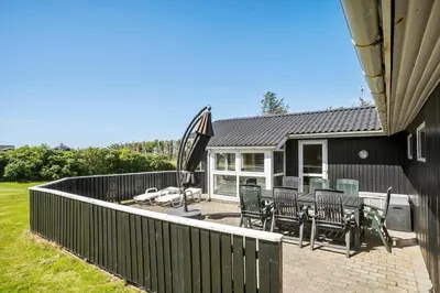 a house with a patio with chairs and an umbrella at LK2071-Lokken-Marensvej-3 in Løkken