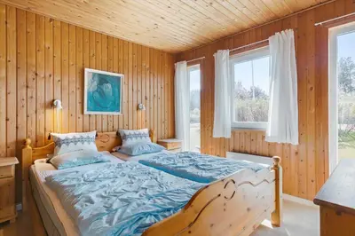 a bed in a room with wooden walls and windows at LK561-Lokken-Lisbethsvej-1 in Løkken