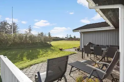 a patio with chairs and a table in a yard at LK561-Lokken-Lisbethsvej-1 in Løkken