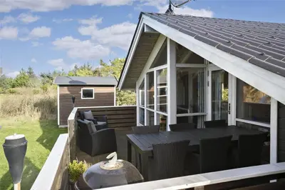 a house with a conservatory with a table and chairs at LK1641-Lokken-Karinavej-3 in Løkken