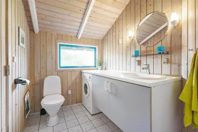 a bathroom with a toilet and a sink and a mirror at LK1641-Lokken-Karinavej-3 in Løkken