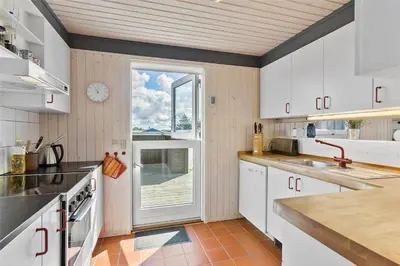 a kitchen with white cabinets and a clock on the wall at LK1793-Lokken-Jettesvej-3 in Løkken