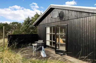 a small black building with a table and a chair at LK2115-Lokken-Marthasvej-7 in Løkken
