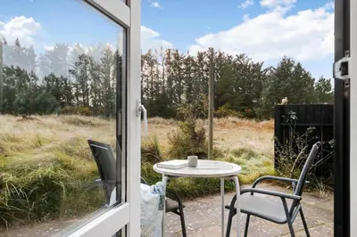 a patio with a table and chairs and a window at LK2115-Lokken-Marthasvej-7 in Løkken