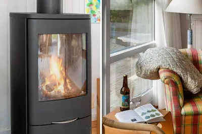 a living room with a fireplace and a bottle of wine at LK2115-Lokken-Marthasvej-7 in Løkken