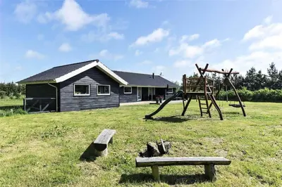 a park with a playground with a bench and a house at LK902-Lokken-Mievej-42 in Løkken