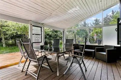 a patio with a glass table and chairs on a deck at LK564-Lokken-Piasvej-17 in Løkken