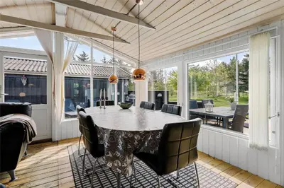 a screened in porch with a table and chairs at LK564-Lokken-Piasvej-17 in Løkken