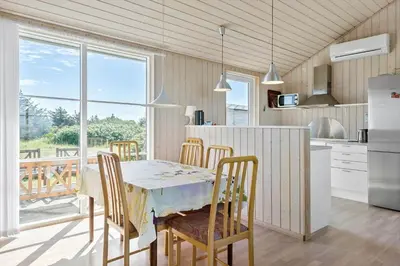 a kitchen with a table and chairs and a kitchen with a window at LK528-Lokken-Rosavej-5 in Løkken
