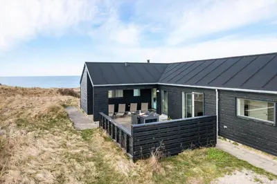 a black house on a hill with the ocean in the background at LK1463-Lokken-Rosavej-11 in Løkken