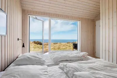 a bedroom with a bed and a large window at LK1463-Lokken-Rosavej-11 in Løkken