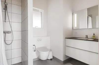 a white bathroom with a toilet and a sink at LK1463-Lokken-Rosavej-11 in Løkken