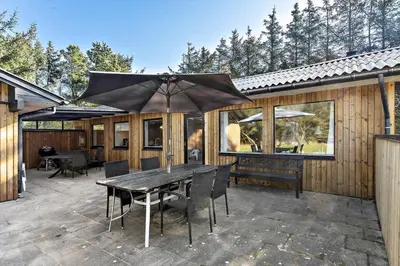 a patio with a table and chairs and an umbrella at LK741-Lokken-Madsinesvej-1 in Løkken