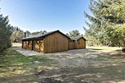 a large wooden building in a yard with trees at LK741-Lokken-Madsinesvej-1 in Løkken