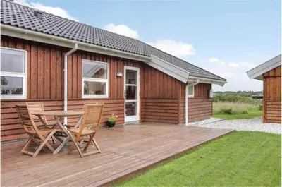 a wooden deck with a table and chairs in front of a house at LK862-Lokken-Olgavej-49 in Løkken