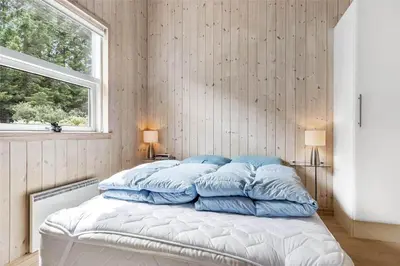 a bedroom with a bed with blue pillows on it at LK862-Lokken-Olgavej-49 in Løkken