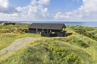 a black house sitting on top of a grassy hill at LK1280-Lokken-Kettrup-Bjerge-Vej-98 in Løkken