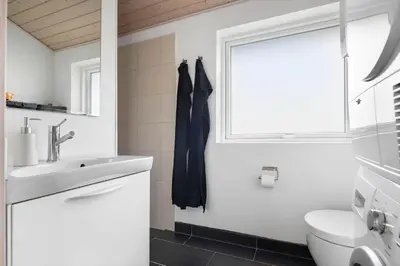 a bathroom with a sink and a toilet and a window at LK784-Lokken-Sinnesvej-7 in Løkken