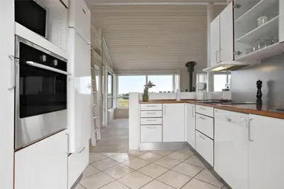 a kitchen with white cabinets and a large window at LK1179-Lokken-Normasvej-6 in Løkken