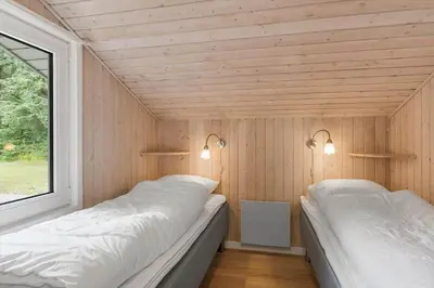 two beds in a room with wooden walls and a window at LK2084-Lokken-Margrethevej-76 in Løkken