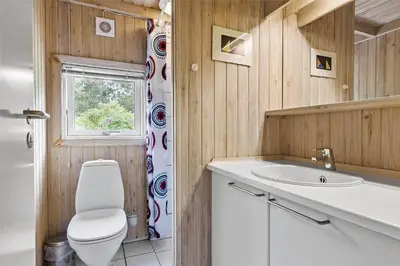 a bathroom with a toilet and a sink and a window at LK626-Lokken-Magdalenevej-40 in Løkken