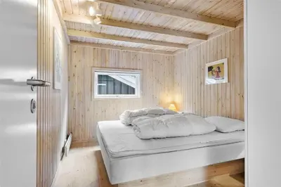 a bed in a room with a wooden ceiling at LK626-Lokken-Magdalenevej-40 in Løkken