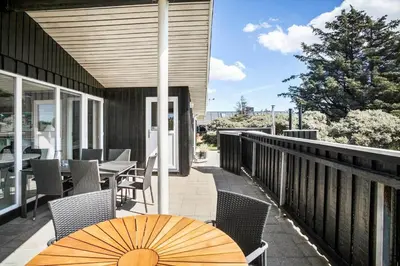a table with an umbrella on a balcony at LK1779-Lokken-Lydiavej-2 in Løkken