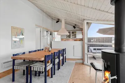 a dining room with a fireplace and a wooden table and chairs at LK1847-Lokken-Ornegaardsvej-17 in Løkken
