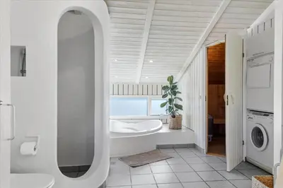 a bathroom with a tub and a sink and a washing machine at LK1847-Lokken-Ornegaardsvej-17 in Løkken