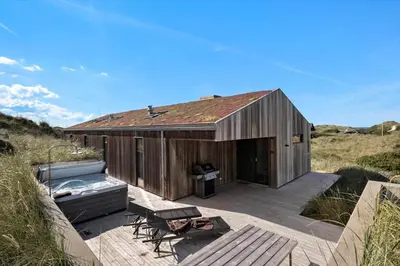 a wooden building with a deck and a grill at LK1272-Lokken-Ruthsvej-17 in Løkken