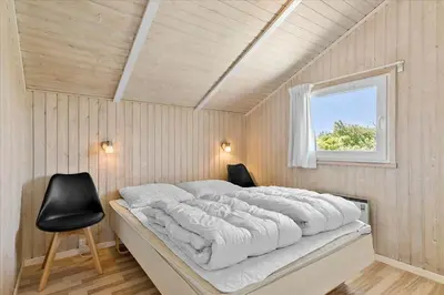 a bedroom with a large bed and a chair at LK431-Lokken-Kettrup-Bjerge-Vej-62 in Løkken